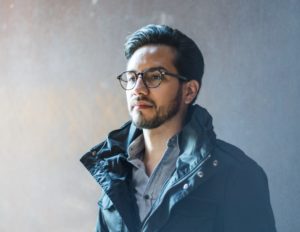 portrait headshot of male model with glasses and jacket with blue and red rusty background