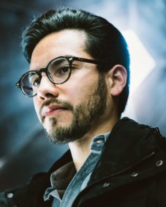 portrait headshot of man wearing glasses with industrial background