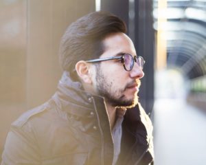 Portrait headshot of model with jacket and glasses looking to the right in a hallway in santa ana
