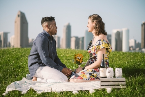 engagement session coronado island picnic san diego skyline california props yellow flowers grass wine glasses