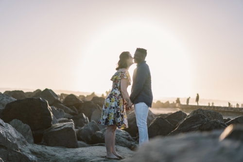 engagement session coronado island sunset san diego california white girl yellow blue red dress african american interracial couple rocks kiss laughing
