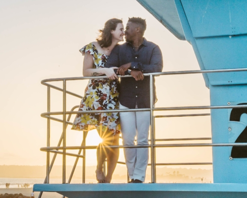engagement session coronado lifeguard tower island sunset san diego california white girl yellow flowers blue red dress african american interracial couple dusk